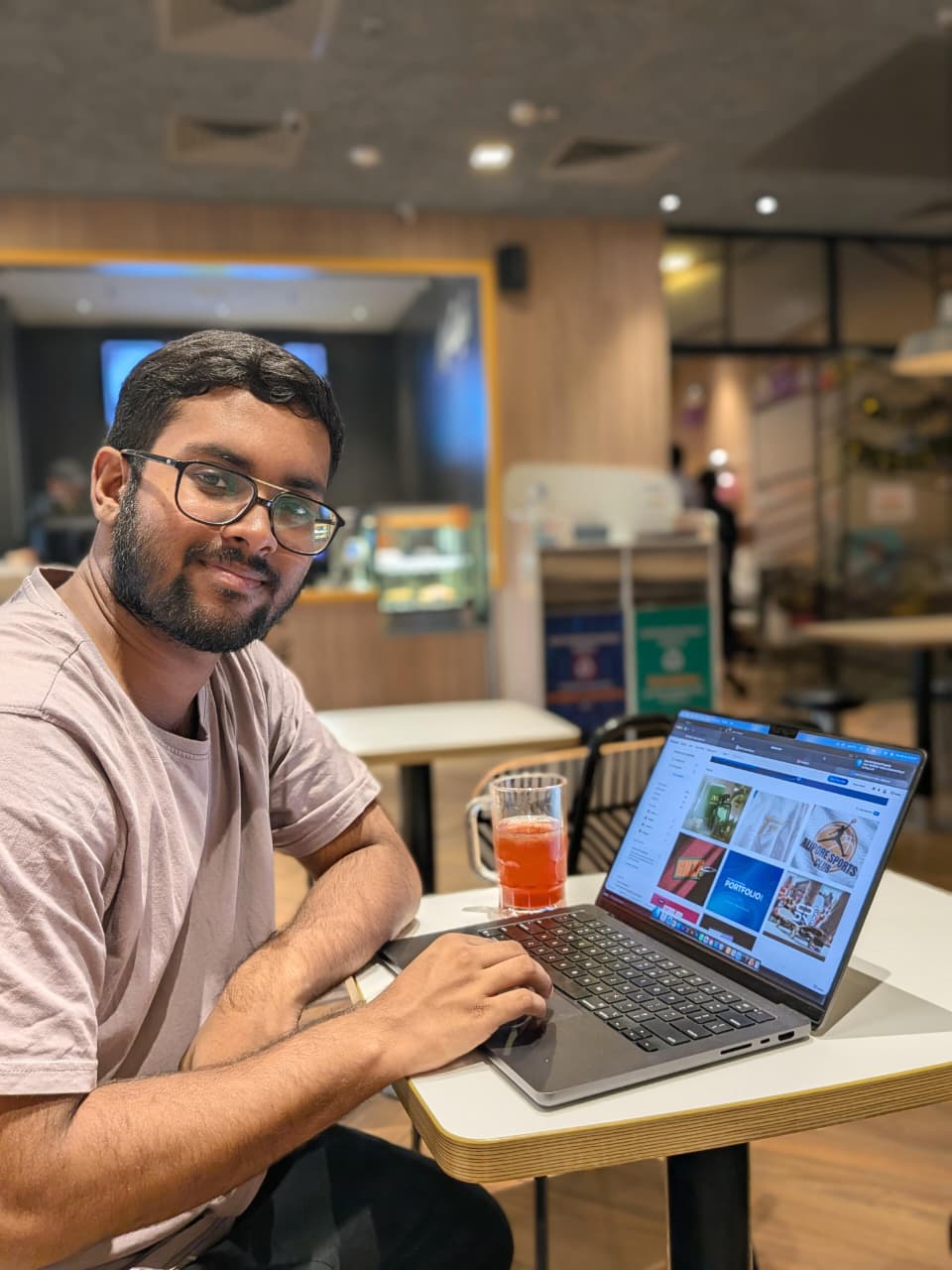 Saikat, Graphic Designer, working on a laptop at a café while reviewing design projects.